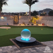 Crystal sphere fountain glowing blue with color-changing LED lights at dusk