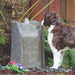 Dog drinking from a Blue Thumb Hollow Springs GFRC boulder fountain