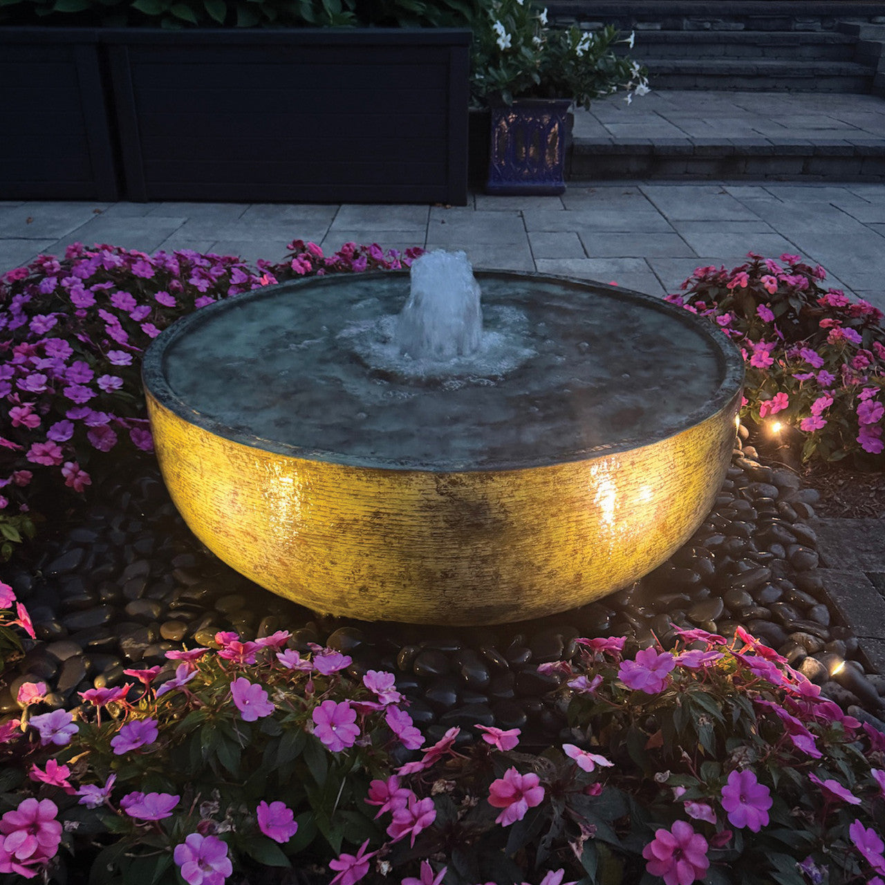 Brass reflection bowl fountain lit at night with fountain lighting