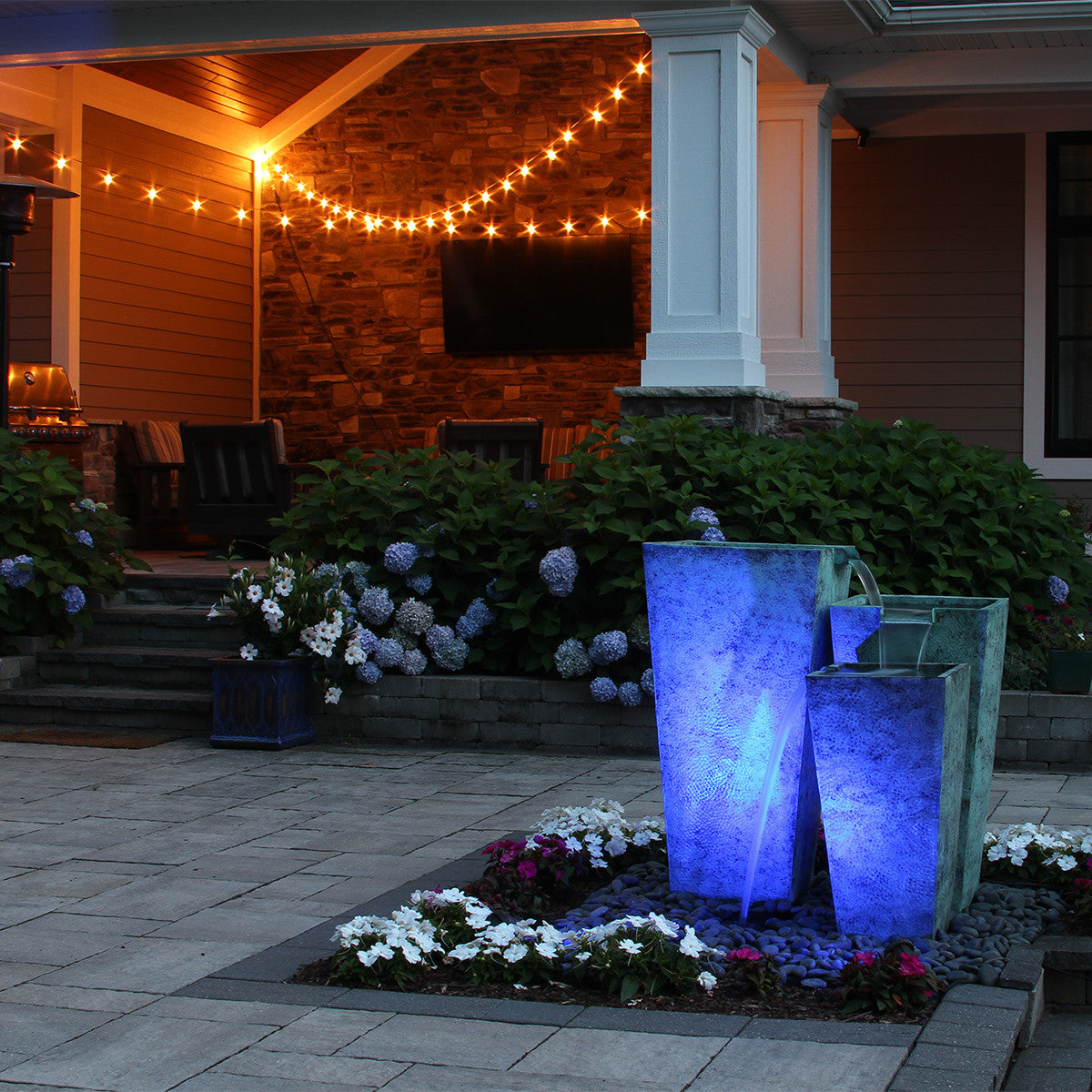 Tapered square triple urn fountain lit at night
