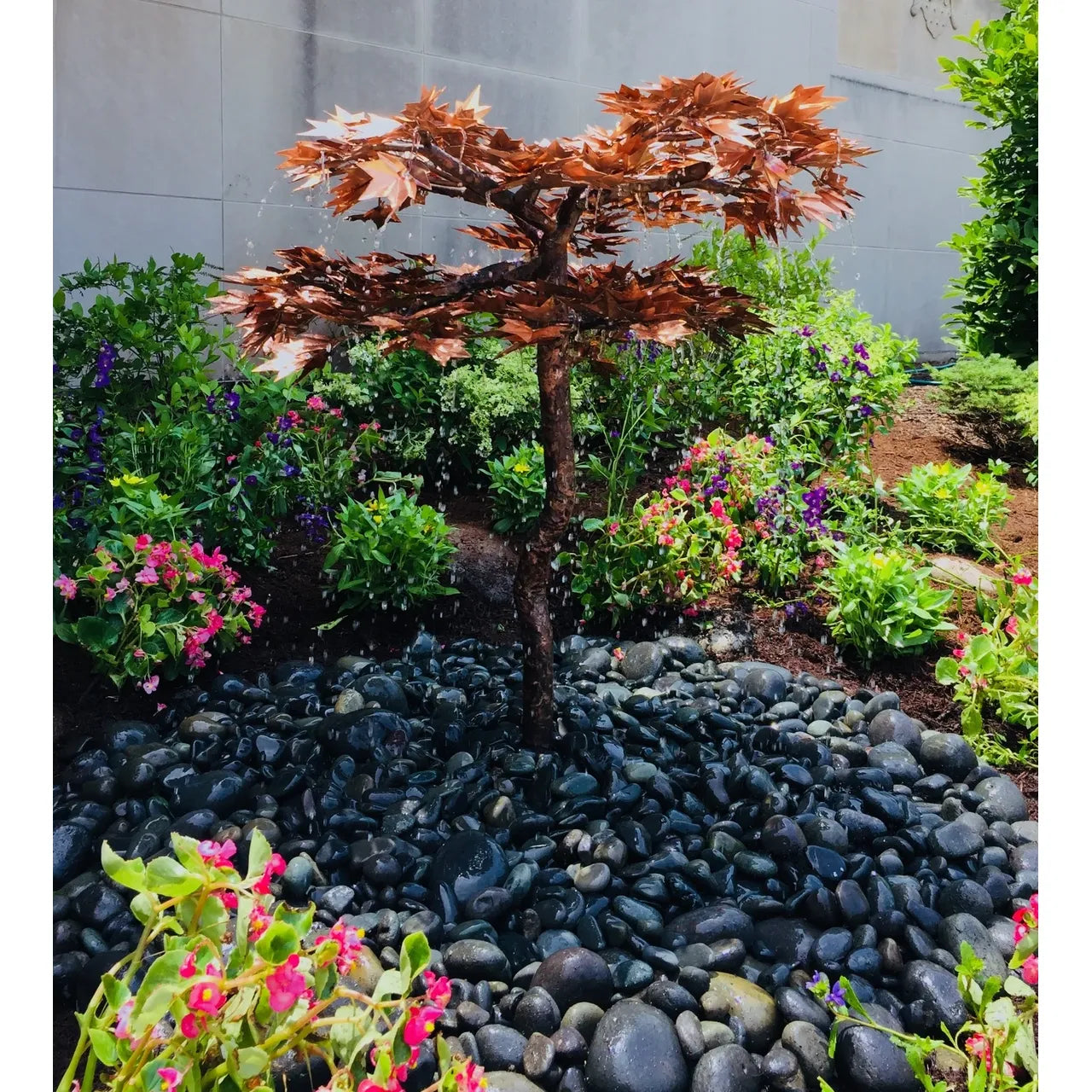 Copper Japanese maple tree fountain installed in a garden