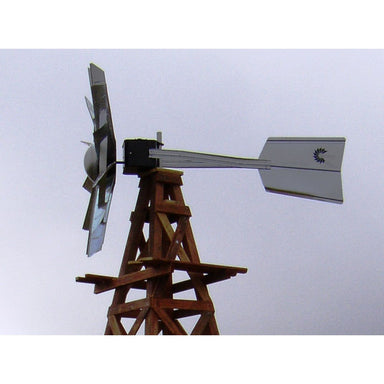 Wooden windmill pond aerator with metal blades against a light blue sky