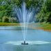 Outdoor Water Solutions Classic Fountain in a lake with trees and grass in the background
