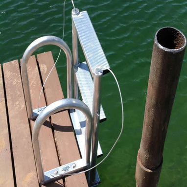 Outdoor Water Solutions Dock Ladder on a wooden dock with water in the background
