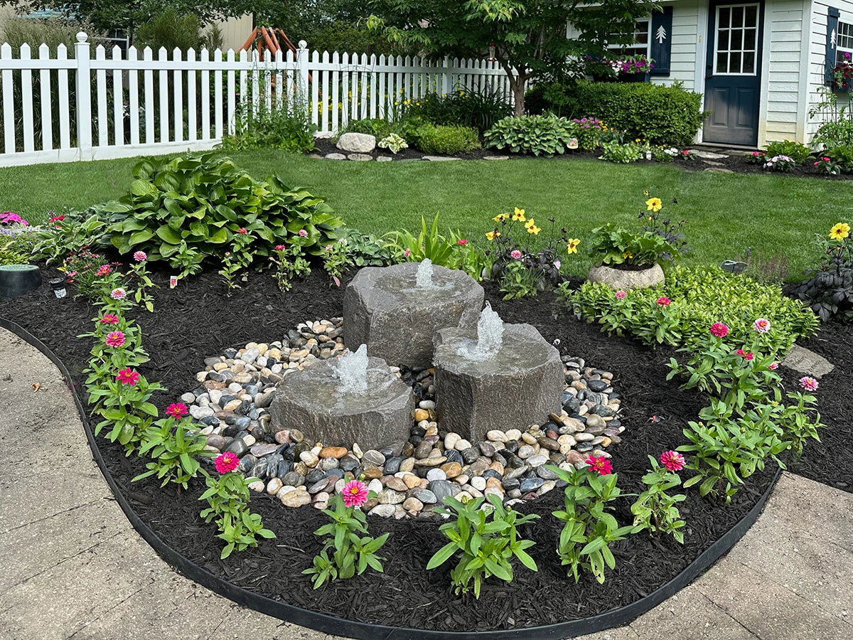 Blue Thumb Triple Falls GFRC boulder fountain kit in a landscaped yard