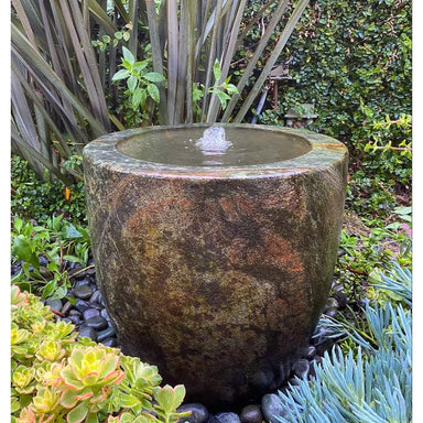 Blue Thumb vessel urn fountain in Brown Patina in a small garden