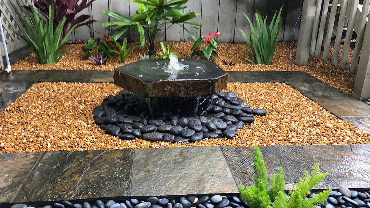 Basalt bird bath fountain installed in a garden