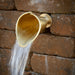 Brass Calla Lily flower spout flowing from a garden wall