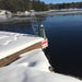 Frozen lake with snow-covered dock and warning sign, surrounded by trees and watel meted using the Ice Away De-Icer