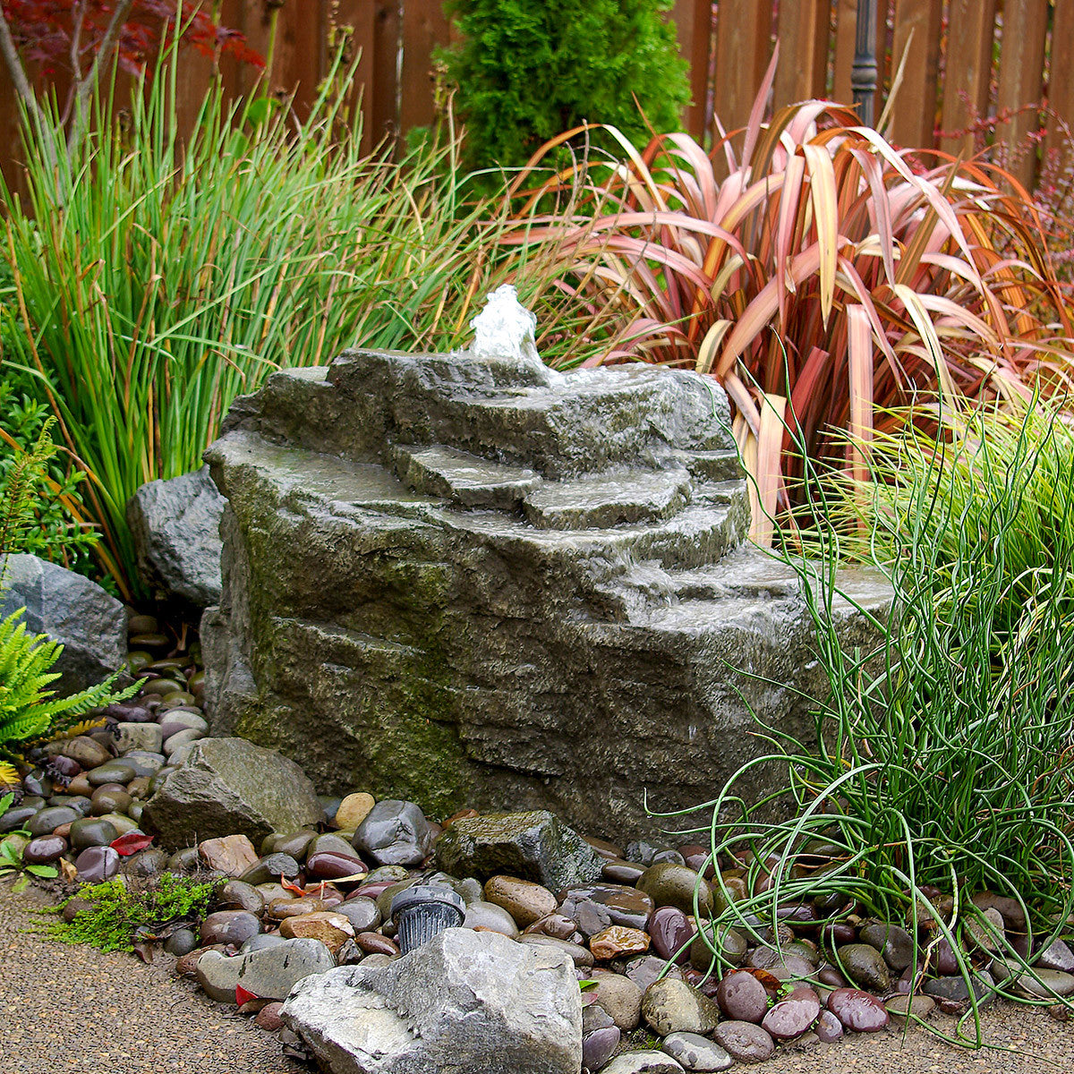 Blue Thumb Mountain Spring GFRC boulder fountain in a landscape
